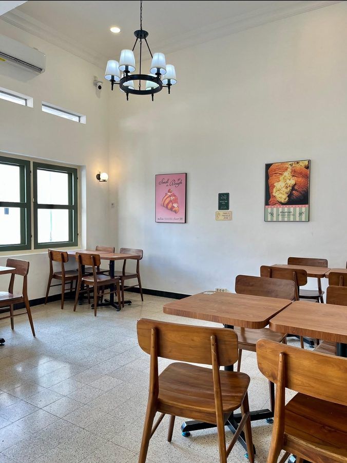 Ruang makan utama Abumain Bake and Bistro dengan langit-langit tinggi dan lampu gantung
